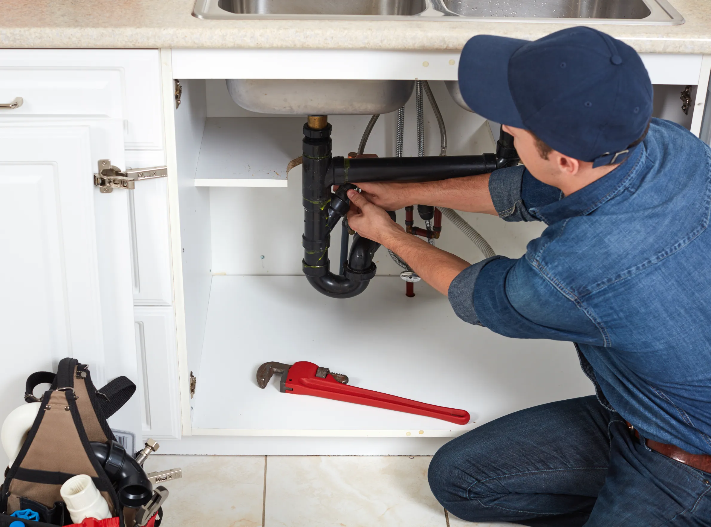 Plumber working on pipes under sink