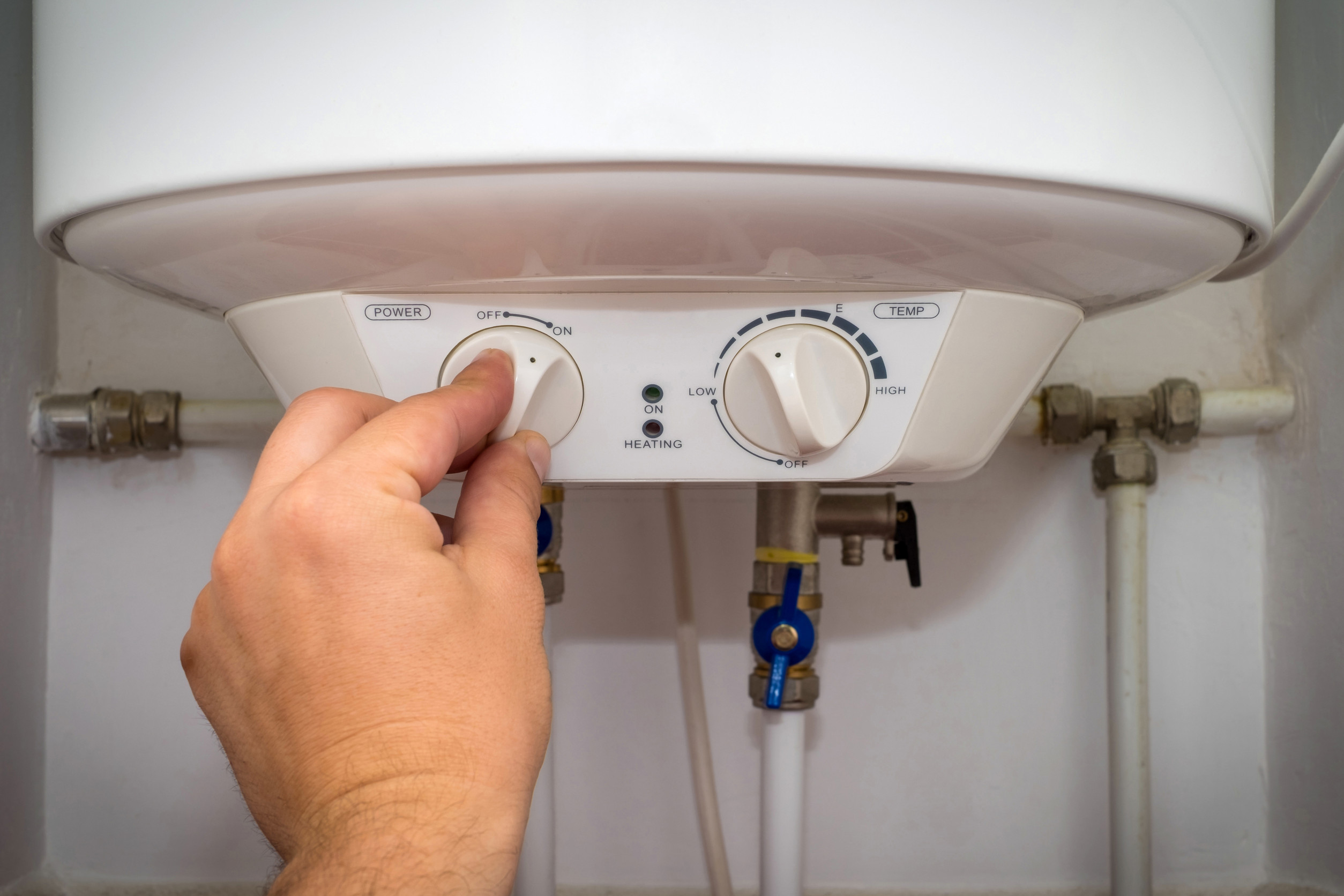 A hand adjusting the temperature settings of a water heater