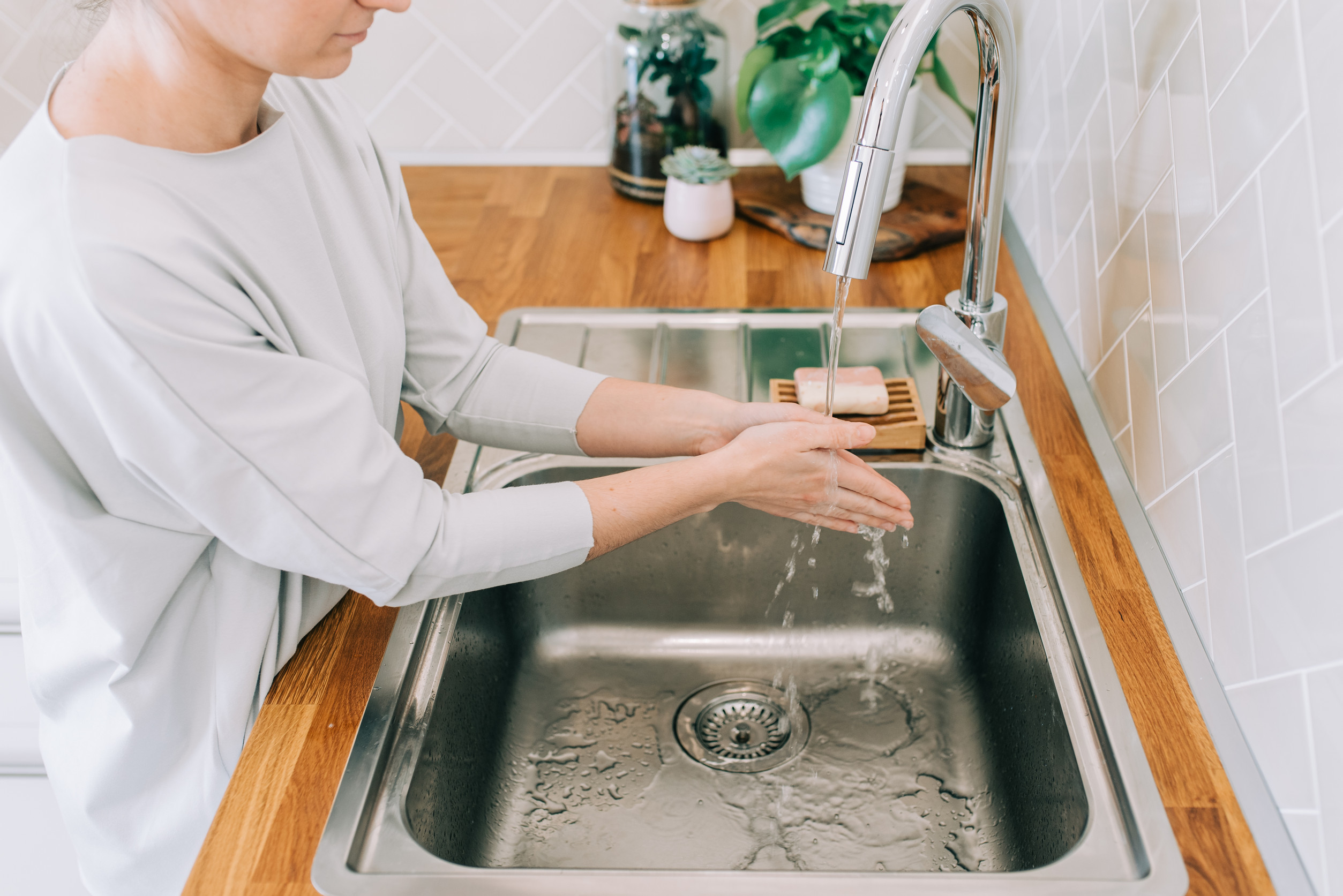 Hygiene to stop spreading coronavirus. Woman washing hands rubbing with soap in sink in kitchen.