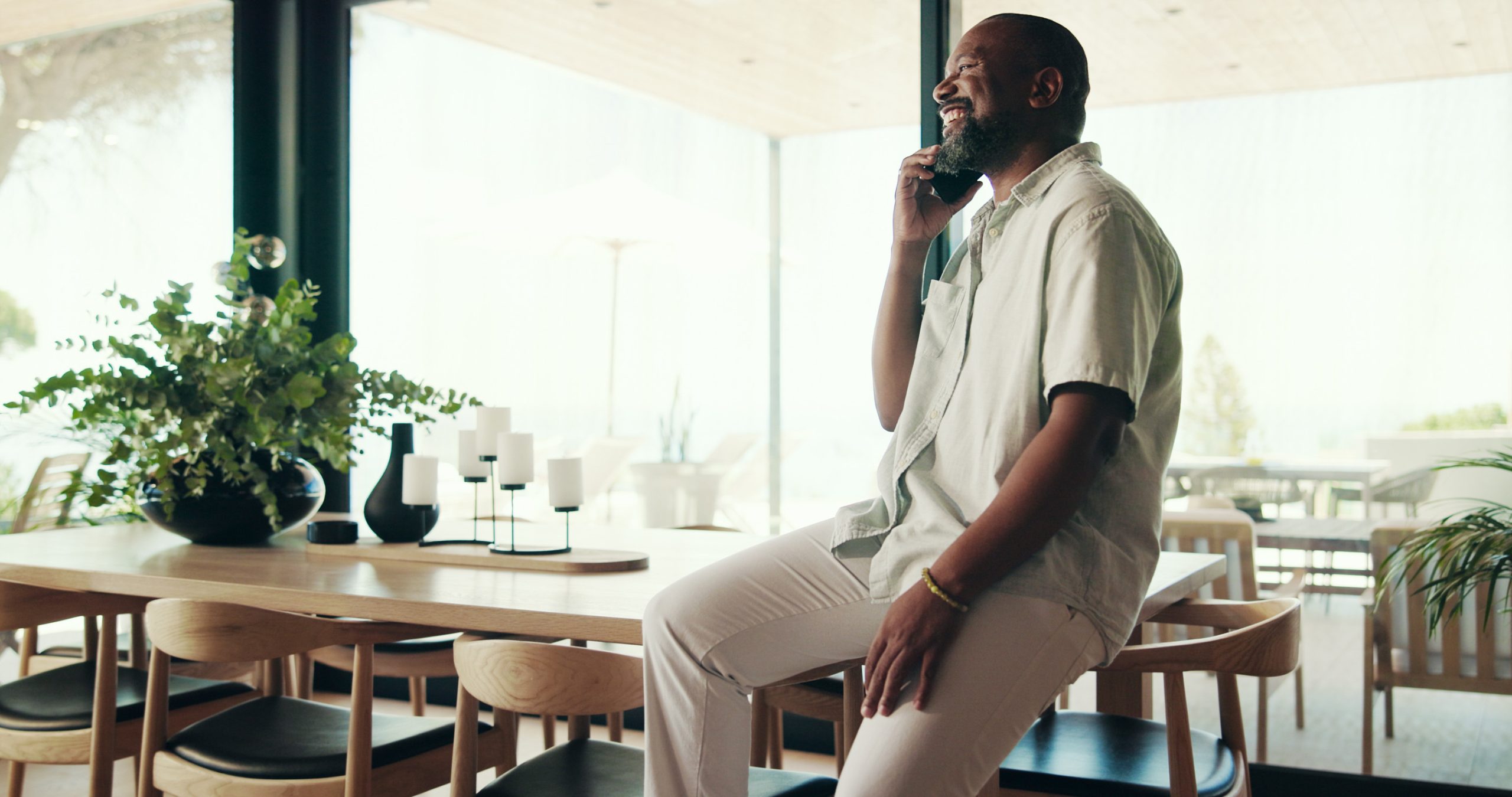 Phone call, house and black man in lounge, smile and planning with network. African person, connection and guy with smartphone, mobile app for chatting and discussion with communication and happiness